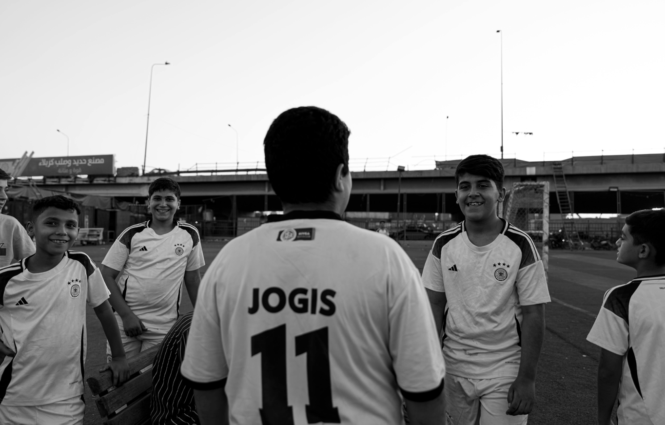 Smiling boys in soccer jerseys gather outdoors at dusk, fostering teamwork.